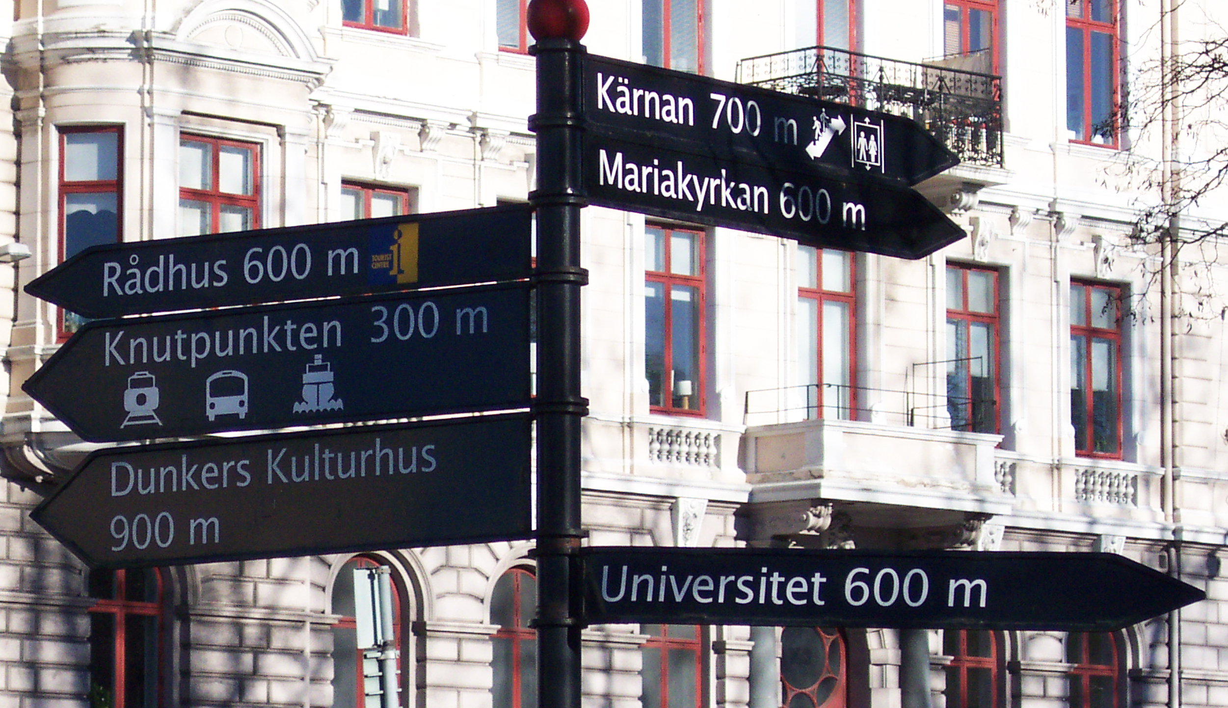 Ett foto som visar vägledningspilar som pekar åt olika håll. En pil visar har texten Universitetet 600 meter.