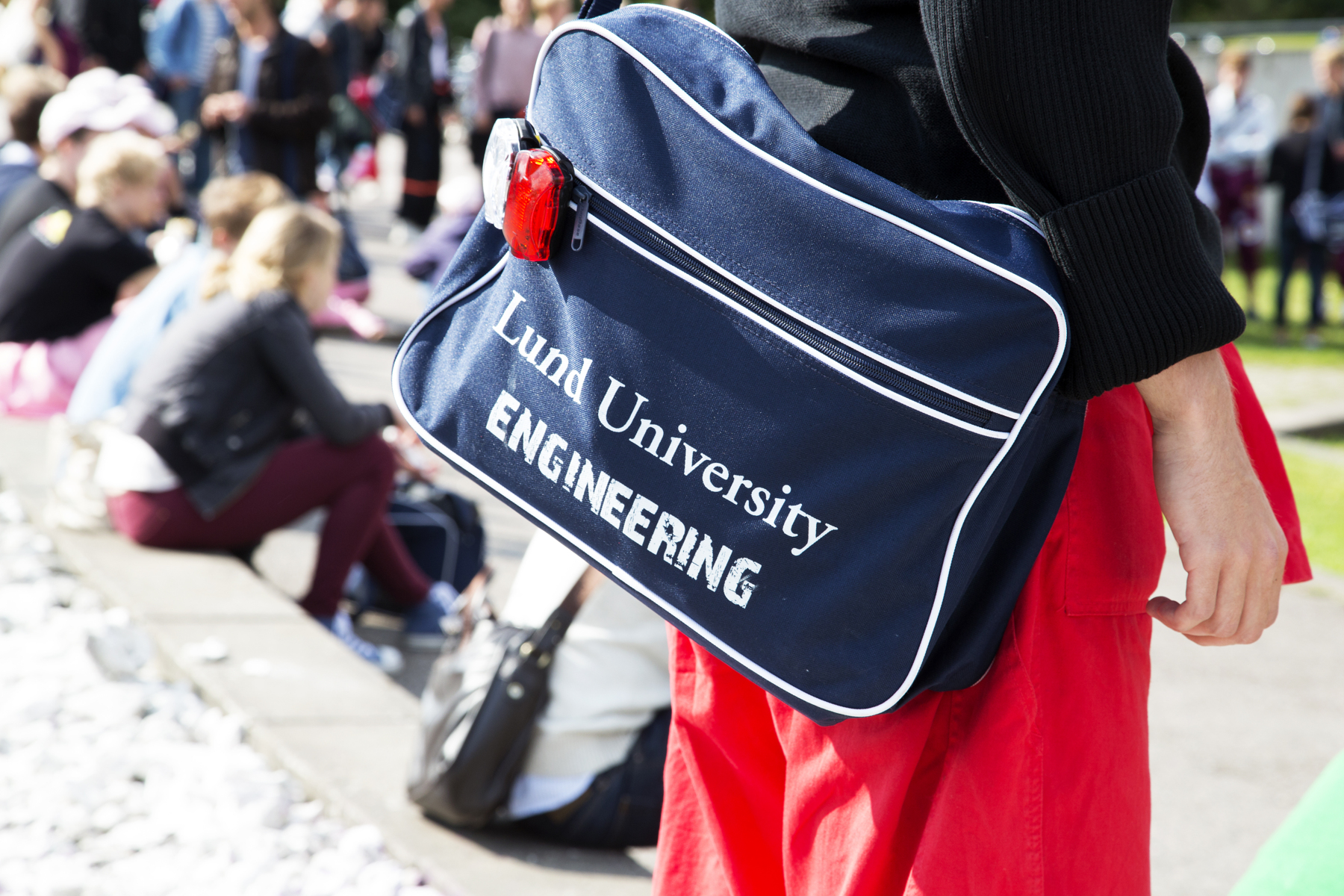 En väska med LTH:s logotyp syns hänga på en persons rygg.